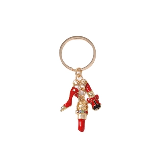 Fashionable golden keychain with red rhinestone high heels and lipstick charms on white background