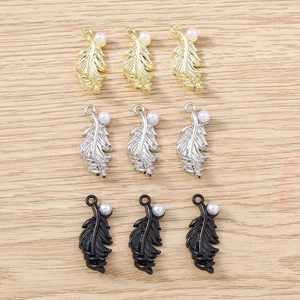 Detail showing feather-shaped DIY charms with pearls in gold, silver, and black finish