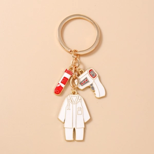 Détail des breloques médicales avec thermomètre et blouse sur porte-clés en métal doré