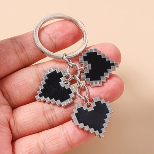 Detail of three black pixel heart charms with silver serrated edges held by hand