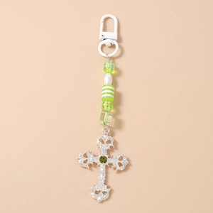 Detail of silver hollow gothic cross with green rhinestone and striped beads keychain