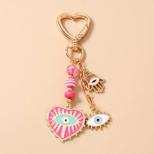 Detail of pink evil eye heart pendant keychain with Hamsa hand and golden metal hardware