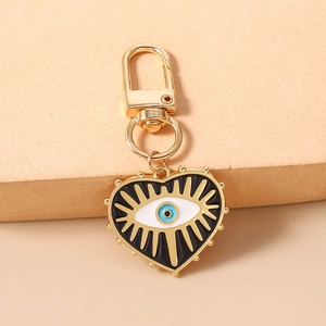Dettaglio di portachiavi a cuore dorato con malocchio in smalto blu su sfondo beige