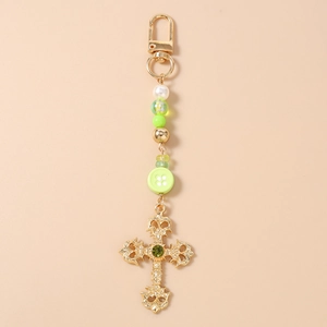 Detail of beaded keychain with green gems, striped beads and golden ornate cross