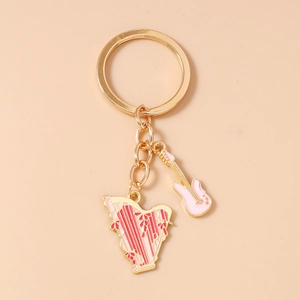 Close-up of pink electric guitar and harp charms on a golden music theme keychain
