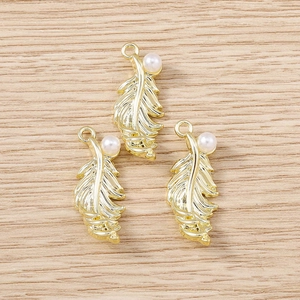 Golden feather pendants with faux pearls for DIY jewelry making on wooden background