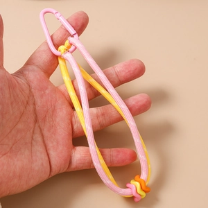 Gros plan du porte-clés tressé rose et jaune avec des perles colorées en main