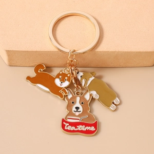 Detail of golden keychain with Shiba Inu and Corgi enamel charms and Tea Time banner