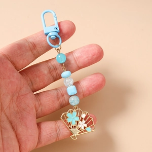Détail du porte-clés perlé bleu avec pendentif éventail sakura doré et mousqueton