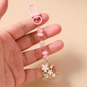 Détail du pendentif éventail sakura rose avec perles sur un porte-clés tenu en main