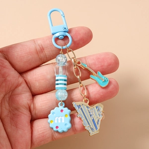 Detail of music themed beaded keychain with light blue guitar, harp and cookie charms