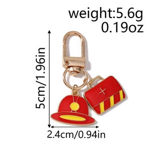Detail of firefighter helmet and first aid kit charms on a golden metal keychain