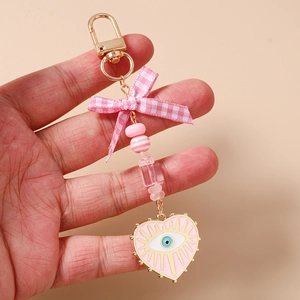 Detailed close-up of pink beaded evil eye keychain with silk bow and heart charm