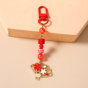 Détail d'un porte-clés à perles rouges avec pendentif éventail et fleurs de cerisier