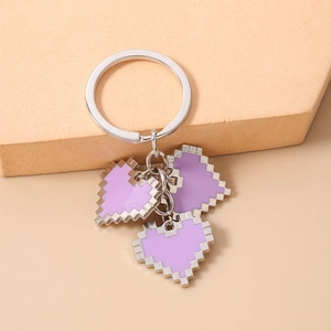 Macro detail of three purple mosaic pixel heart charms on a silver metal keychain