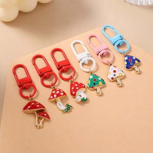 Set of six colorful mushroom keychains with pearl charms and lobster clasps on yellow background