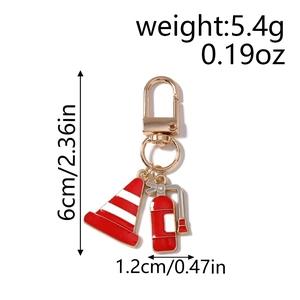 Detail view of metal keychain featuring red fire extinguisher and traffic cone pendants