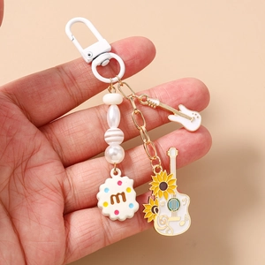 Close-up of music themed keychain with guitar and biscuit charms on a hand