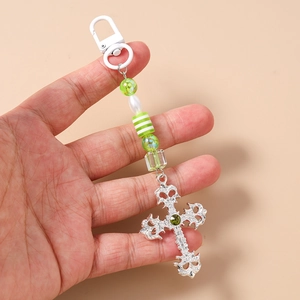 Detail of gothic silver cross keychain with green beads and ornate metal engraving