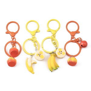 Realistic resin fruit keychains featuring yellow bananas and orange peaches on white background