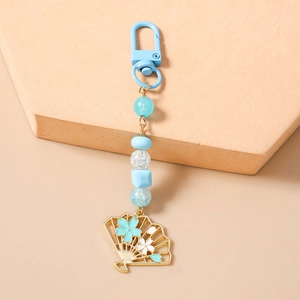 Détail d'un porte-clés perlé bleu avec éventail doré et motifs de fleurs de cerisier