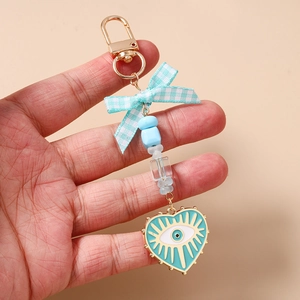 Detailed view of light blue beaded keychain with checkered bow and evil eye heart charm
