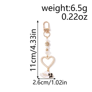 Detail view of pearl heart keychain with hat charm and dimensions 11cm x 2.6cm