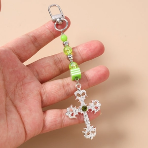 Detail of silver hollow cross keychain with green beads and central emerald gemstone