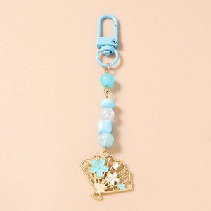 Détail du porte-clés perlé avec perles carrées bleues et pendentif éventail doré