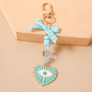 Beaded keychain with blue evil eye heart pendant and plaid bow on a display stand