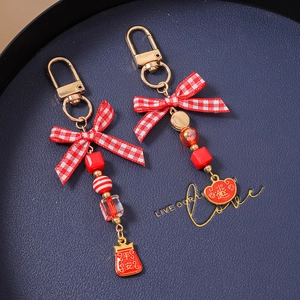 Close-up of red beaded keychains with gold enamel charms and festive bow detail