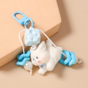Detail of white plush bunny keychain with blue bow, cheese bead and golden clasp