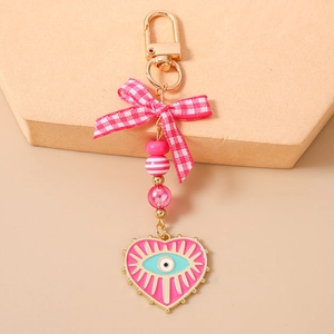 Close-up of pink beaded keychain with checkered ribbon bow and evil eye heart charm