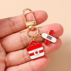 Detail of medical nurse keychain featuring golden lobster clasp with aid kit and plaster charm