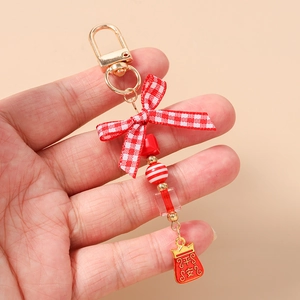 Detailed close-up of a beaded keychain with a red checkered bow and Pingan charm