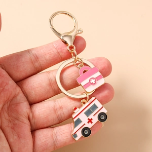 Detail eines medizinischen Schlüsselanhängers mit rosa Emaille-Krankenwagen und Erste-Hilfe-Set