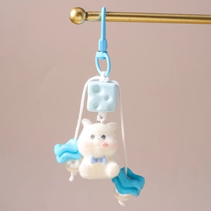 Detailed macro view of white plush bear keychain with blue bow and pearl bead decor