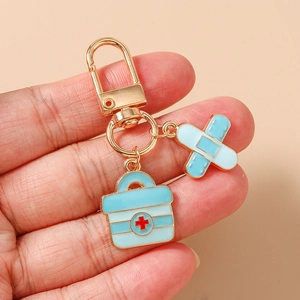 Detail of medical theme keychain with first aid kit and bandage charms on a hand