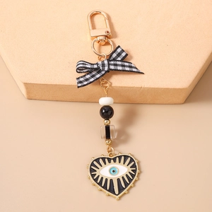 Detail of beaded evil eye heart keychain with black and white bow on stone background