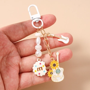 Detailed view of beaded keychain with white guitar charms and round cookie pendant