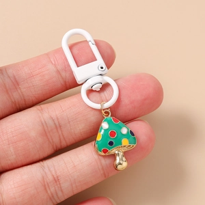 Detail of green mushroom keychain with colorful spots and a white carabiner clip