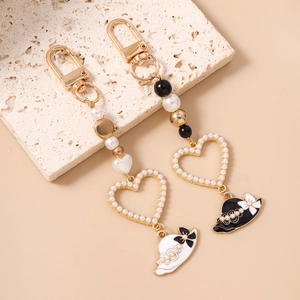 Fashionable heart pearl keychains with beads and enamel hat charms on stone surface