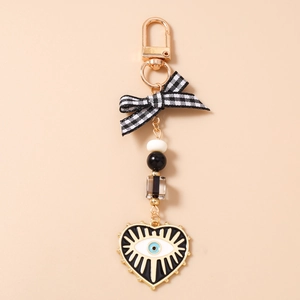 Close-up of beaded evil eye heart keychain with black white bow and gold clasp