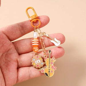 Detail of beaded keychain with guitar, violin and cookie charms on golden chain