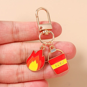 Detail of firefighter keychain with fire flame charm and red fire bucket pendant on gold hook