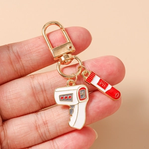 Macro detail of medical keychain with thermometer and test tube charms in gold enamel
