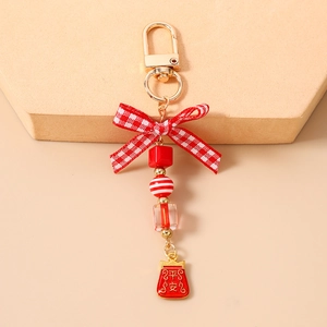Detail of red beaded keychain featuring a bow and red lucky bag with Pingan characters