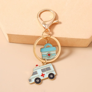 Detail eines medizinischen Schlüsselanhängers mit blauer Erste-Hilfe-Box und Krankenwagen