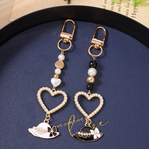Detail of luxury heart and hat charms with pearls and enamel on gold keychains