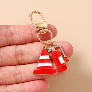 Detailed view of enamel keychain featuring a red fire extinguisher and traffic cone charm